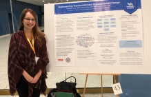 Samantha Koury in front of ITTIC's Implementing Trauma-Informed Organizational Change poster. 